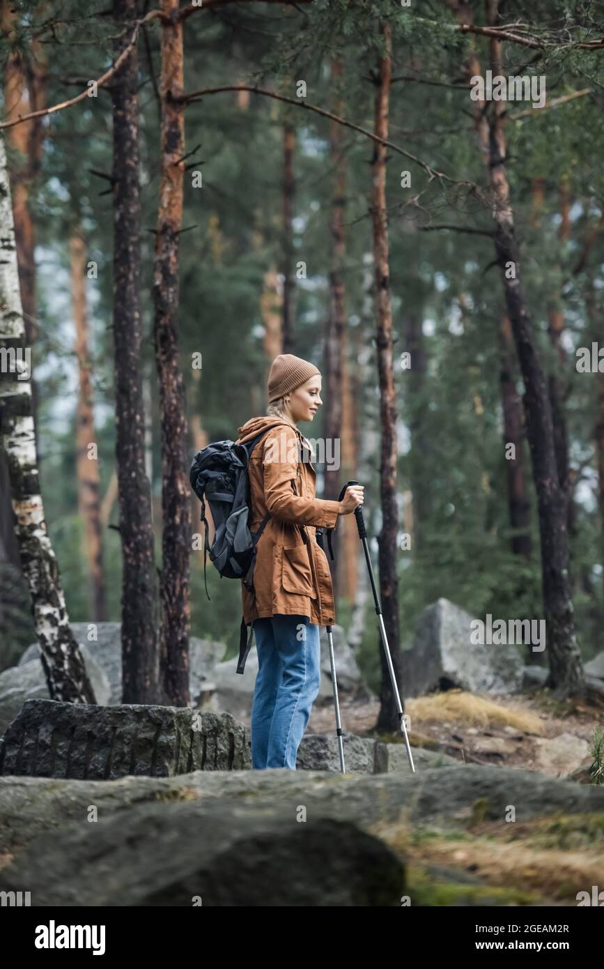 giovane donna in piedi cappello con bastoni da trekking e zaino in foresta  Foto stock - Alamy