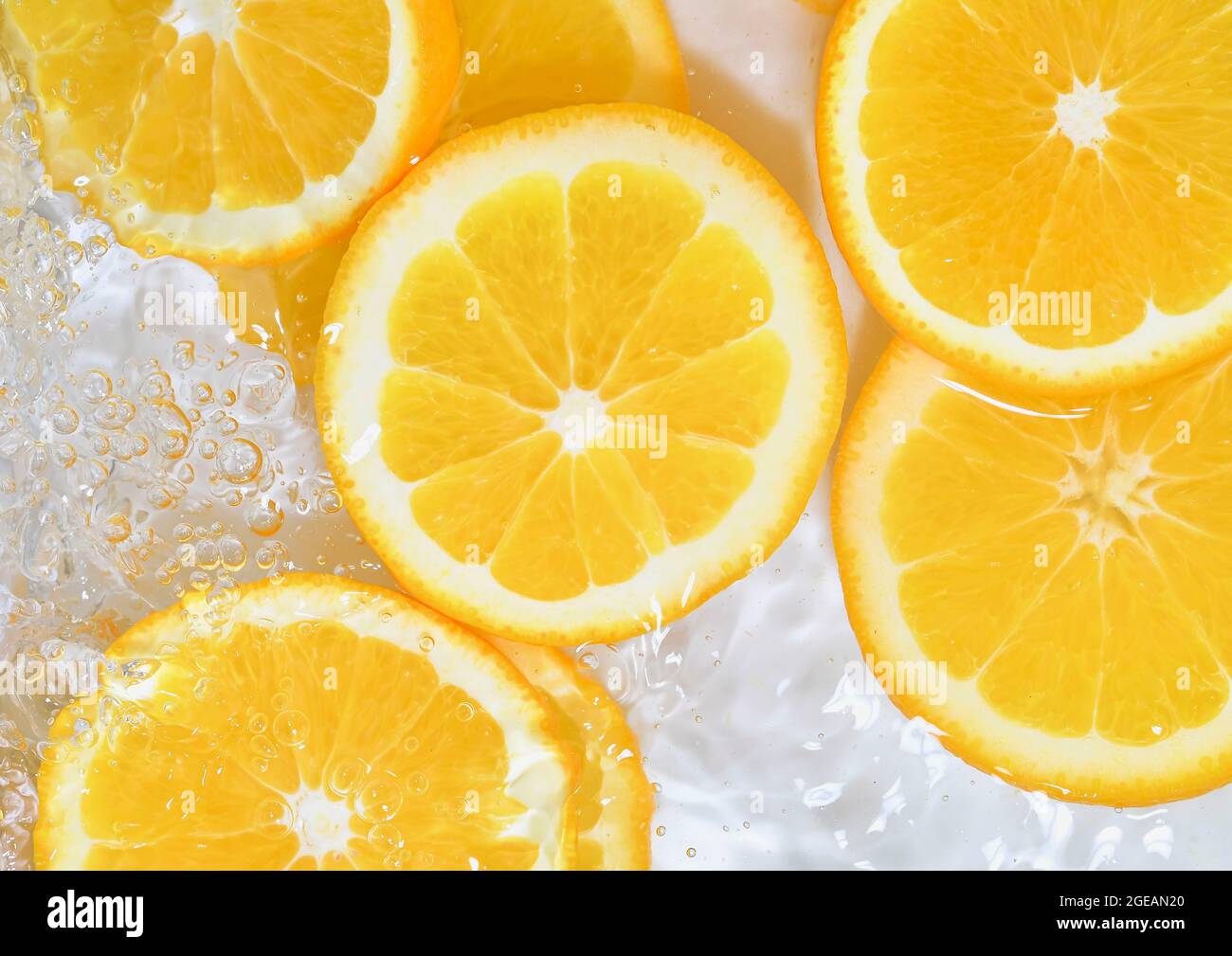 Primo piano di arance in liquido con bolle. Fette di arance succose in acqua. Primo piano fette fresche di arance su sfondo bianco Foto Stock
