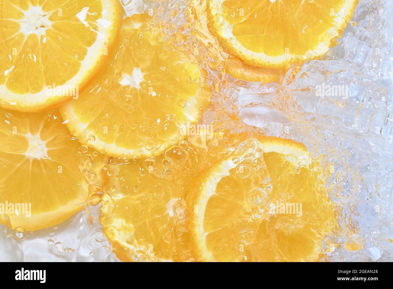 Primo piano di arance in liquido con bolle. Fette di arance succose in acqua. Primo piano fette fresche di arance su sfondo bianco Foto Stock