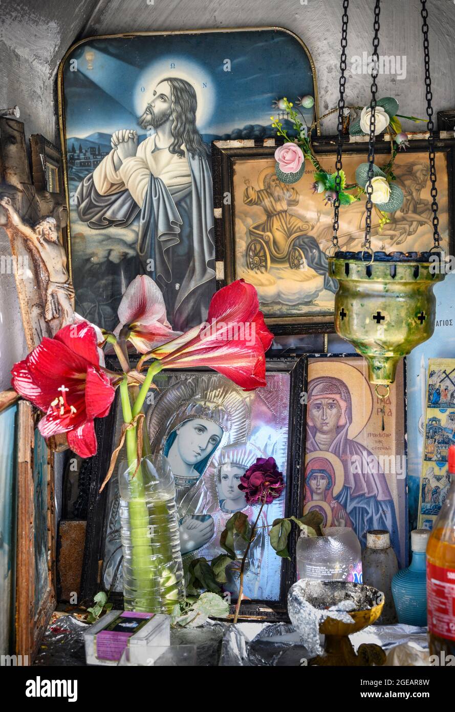 L'interno di un santuario greco ortodosso, a bordo strada, che mostra icone religiose, bottiglie di olio santo e bruciatori di incenso. Arcadia, Peloponneso, Grecia Foto Stock