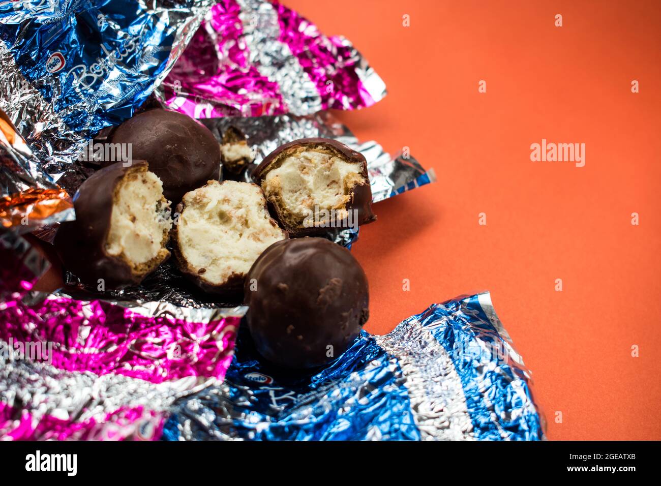 Alcuni cioccolatini e alcuni diversi involucri colorati sulla superficie arancione Foto Stock