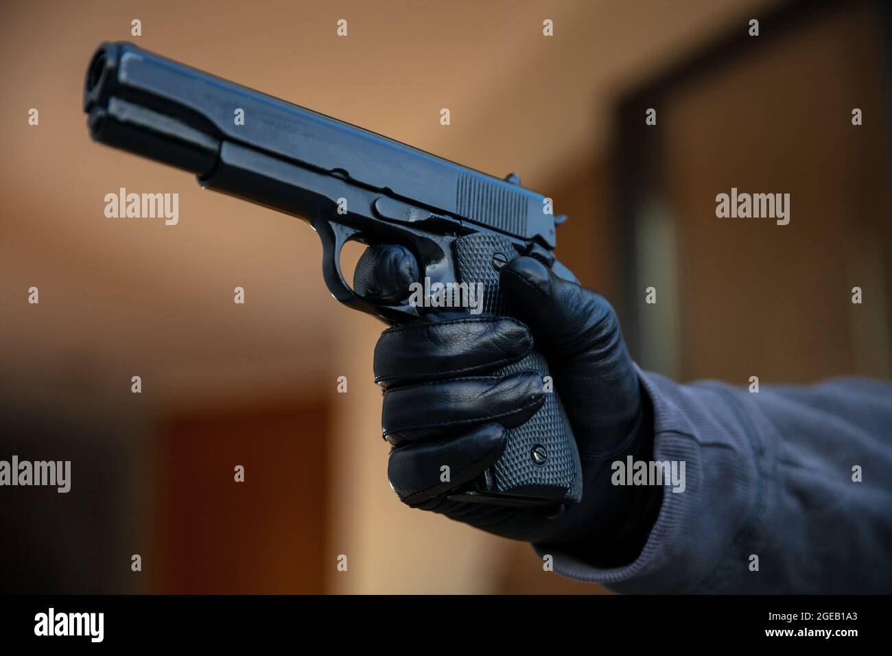 Pistola in mano guanto. Gunman indossa guanti in pelle che puntano con una  pistola, sfocano lo sfondo interno, vista closeup. Concetto killer,  assassino Foto stock - Alamy