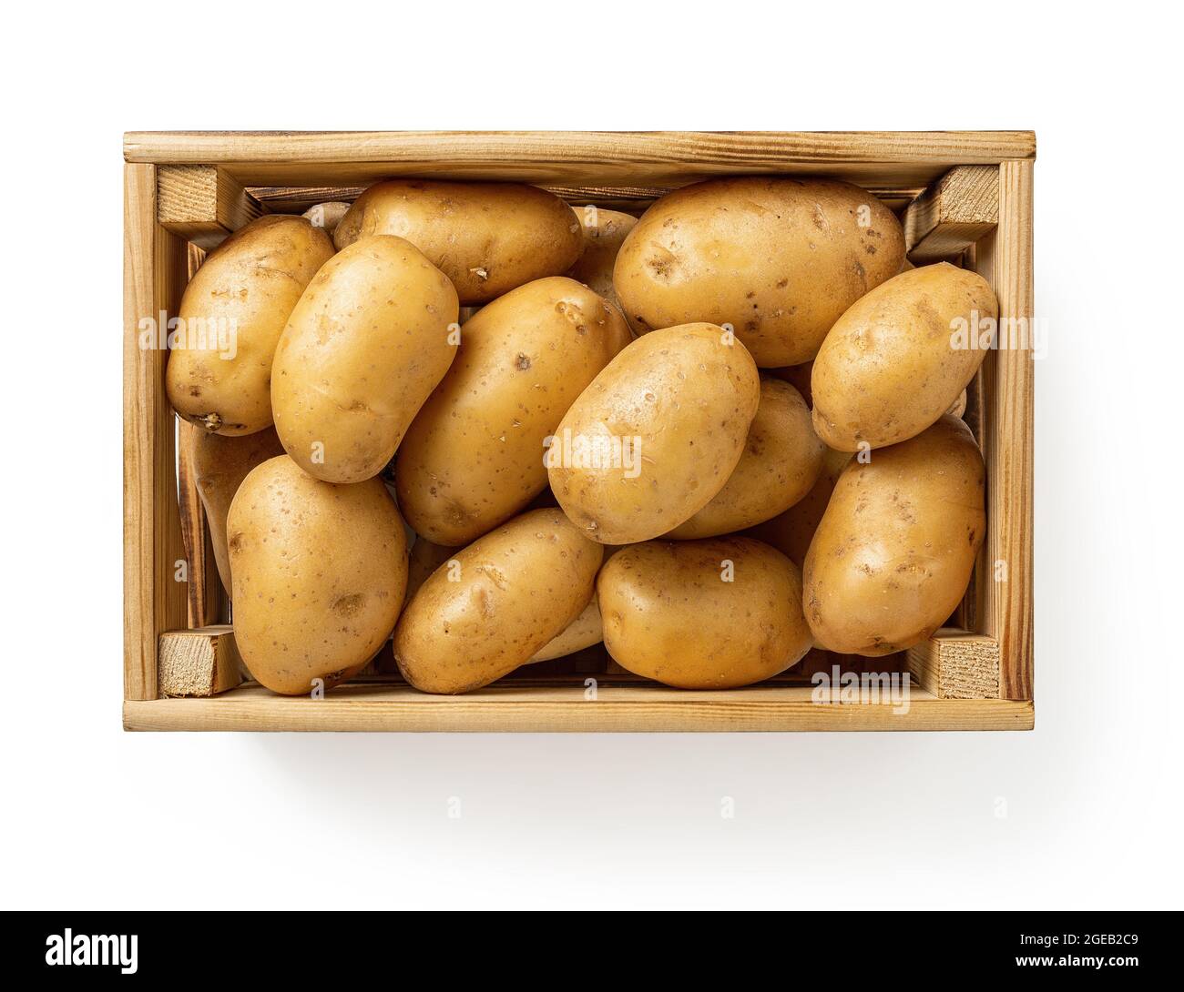 Patate gialle crude in una cassa di legno isolata su sfondo bianco. Tuberi di patate freschi in una scatola di legno. Contenitori rustici per verdure. Foto Stock