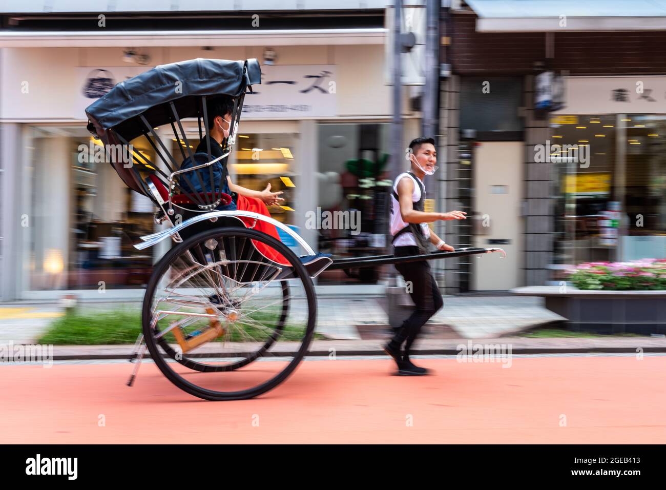 Un risciò trainato o una jinrikisha trasporta i turisti intorno al tempio buddista di Sensoji e allo storico quartiere di Asakusa a Tokyo, Giappone. Foto Stock