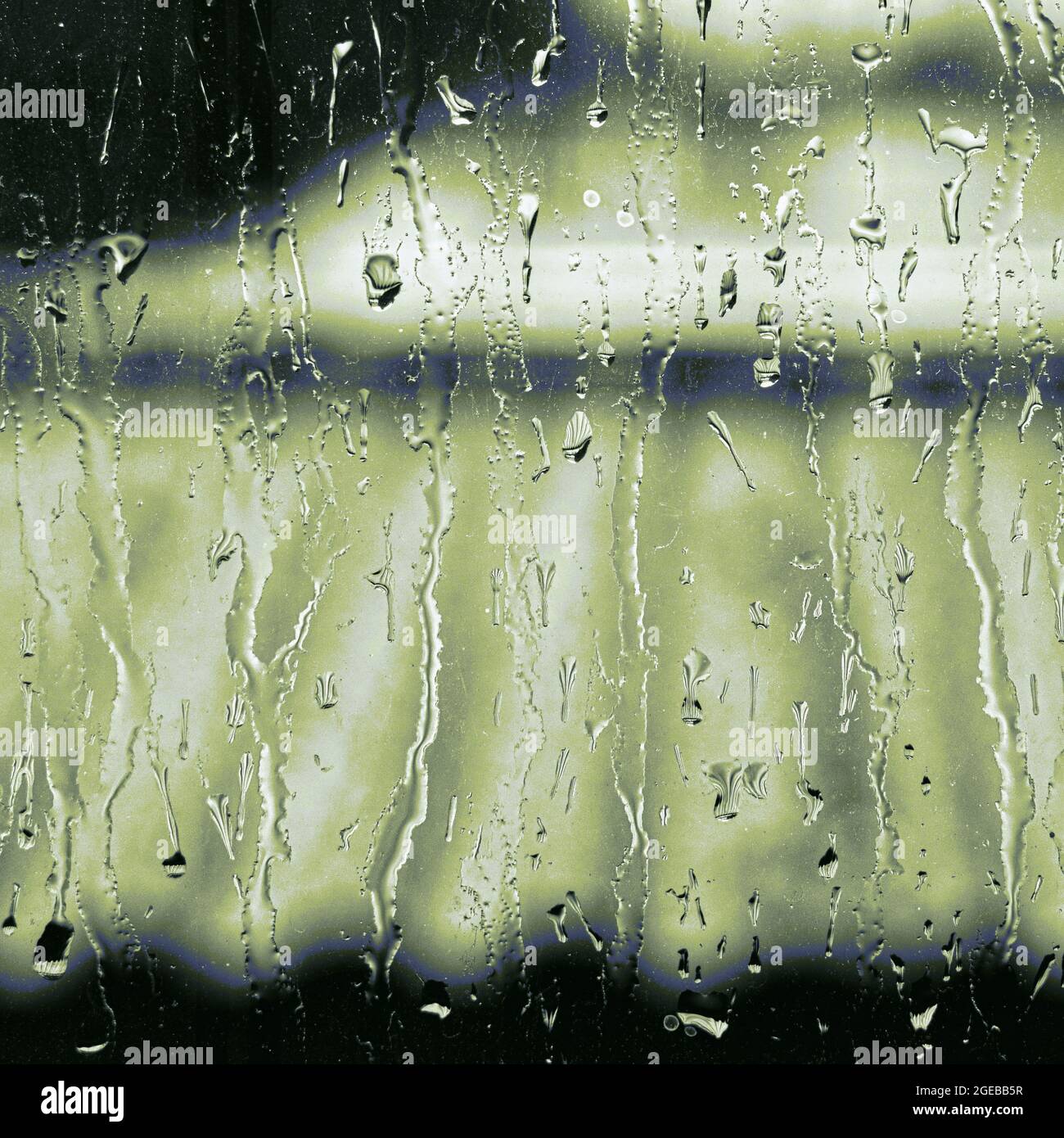 La pioggia stride su un dolore della finestra in giornata coperto con la prospettiva verde cupa sopra un motivo corrugato. Come la pioggia verde, creando un modello astratto. Foto Stock