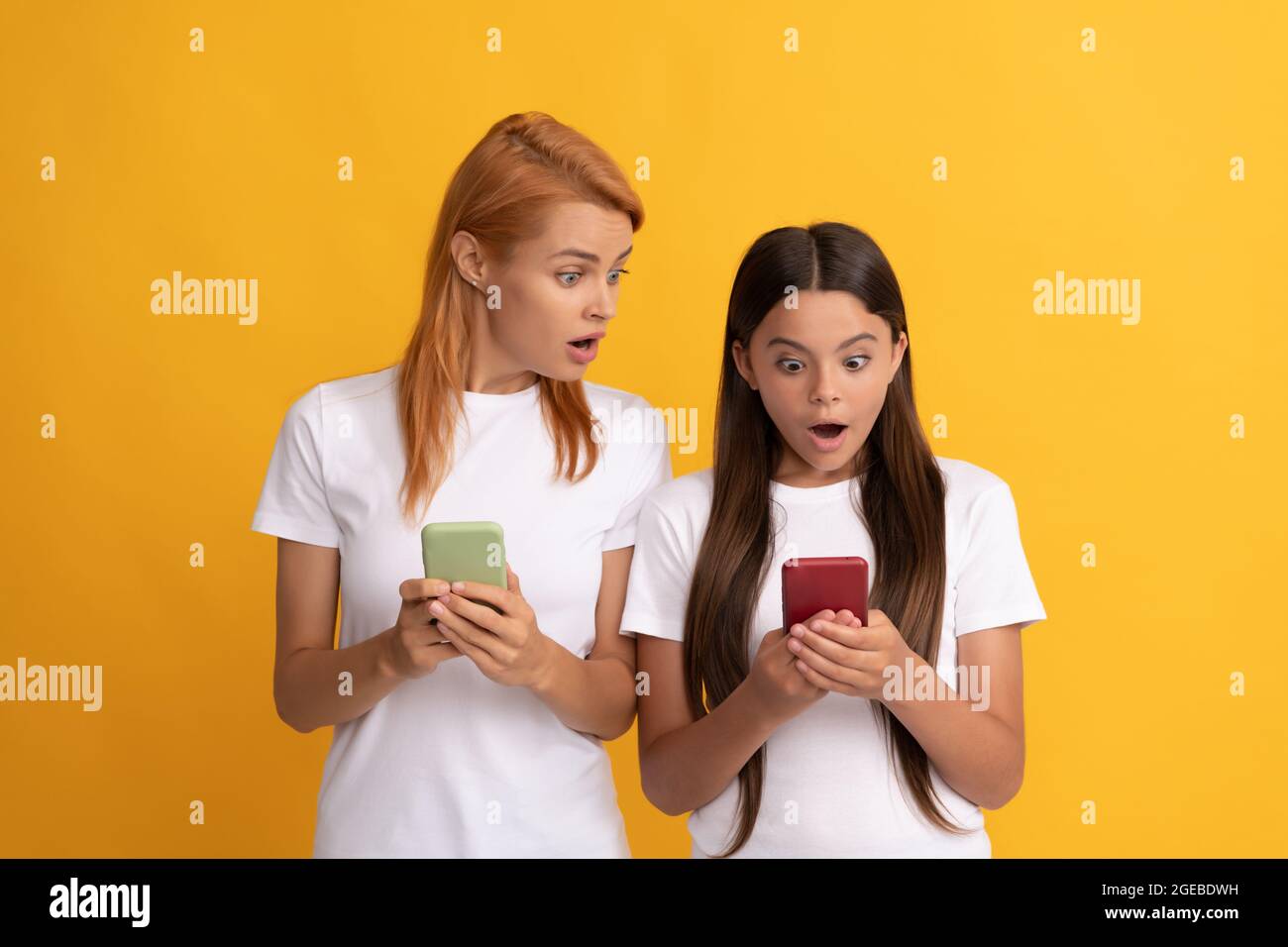 mamma e bambina sorpresi che chattano online utilizzando uno smartphone moderno, chattano Foto Stock