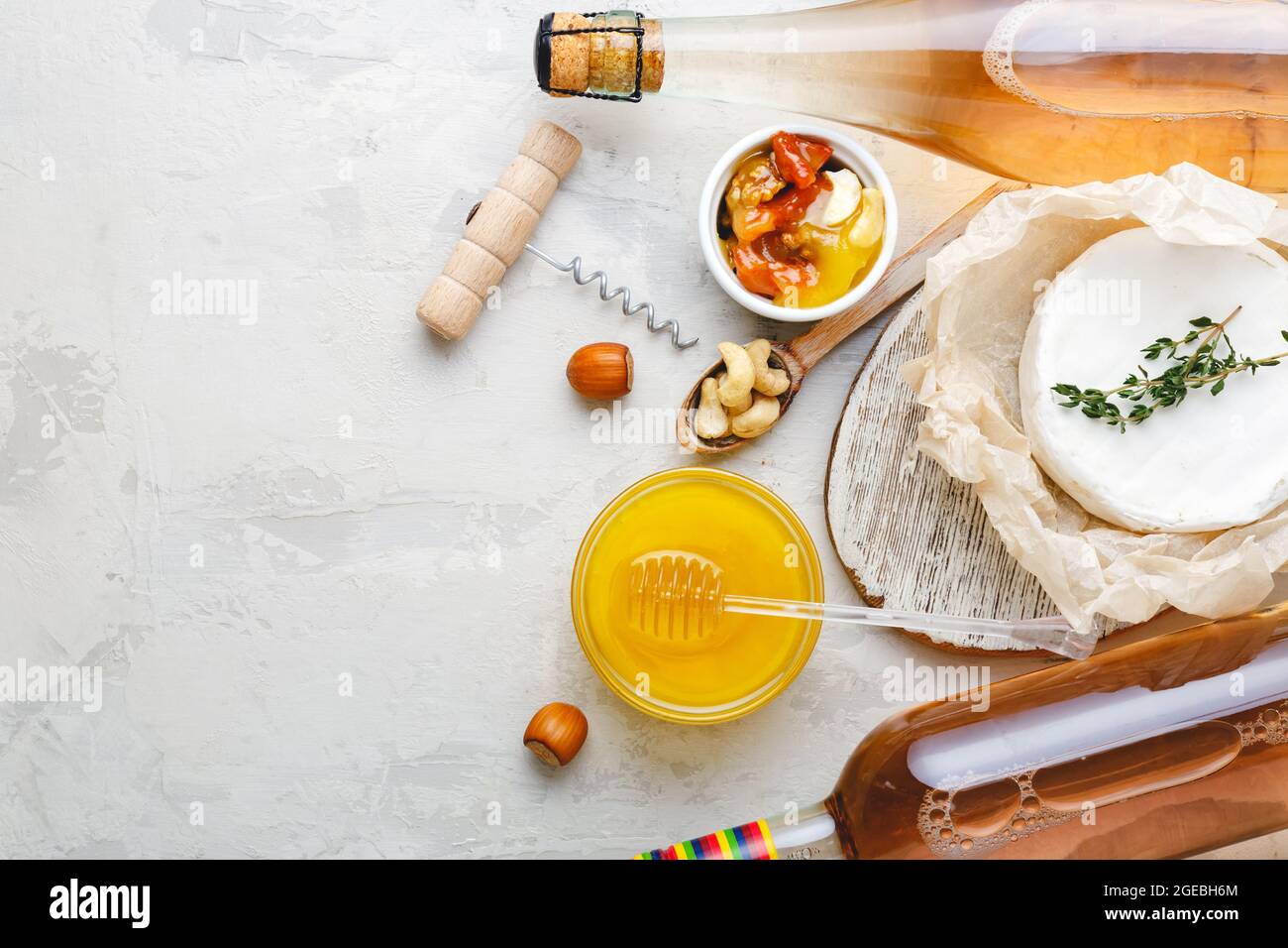 Vino rosa champagne miele brie formaggio noci spuntini antipasto su sfondo di pietra grigio chiaro. Bevande mediterranee per cena con festa del vino. Foto Stock