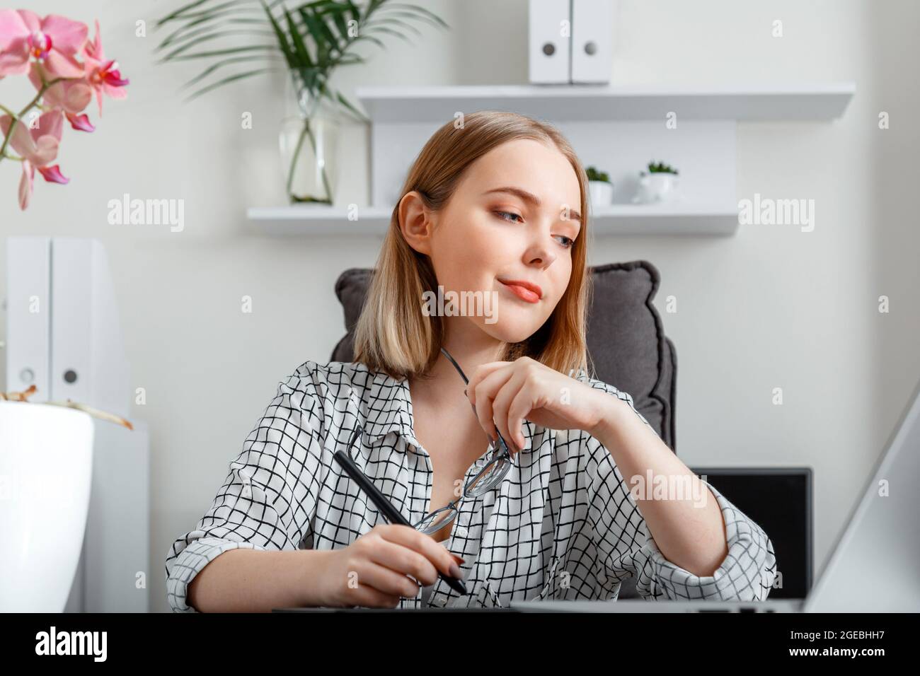 Giovane donna freelance grafico che lavora utilizzando grafica tablet e laptop in casa ufficio interni. Bionda caucasica fiduciosa focalizzata donna che fa Foto Stock