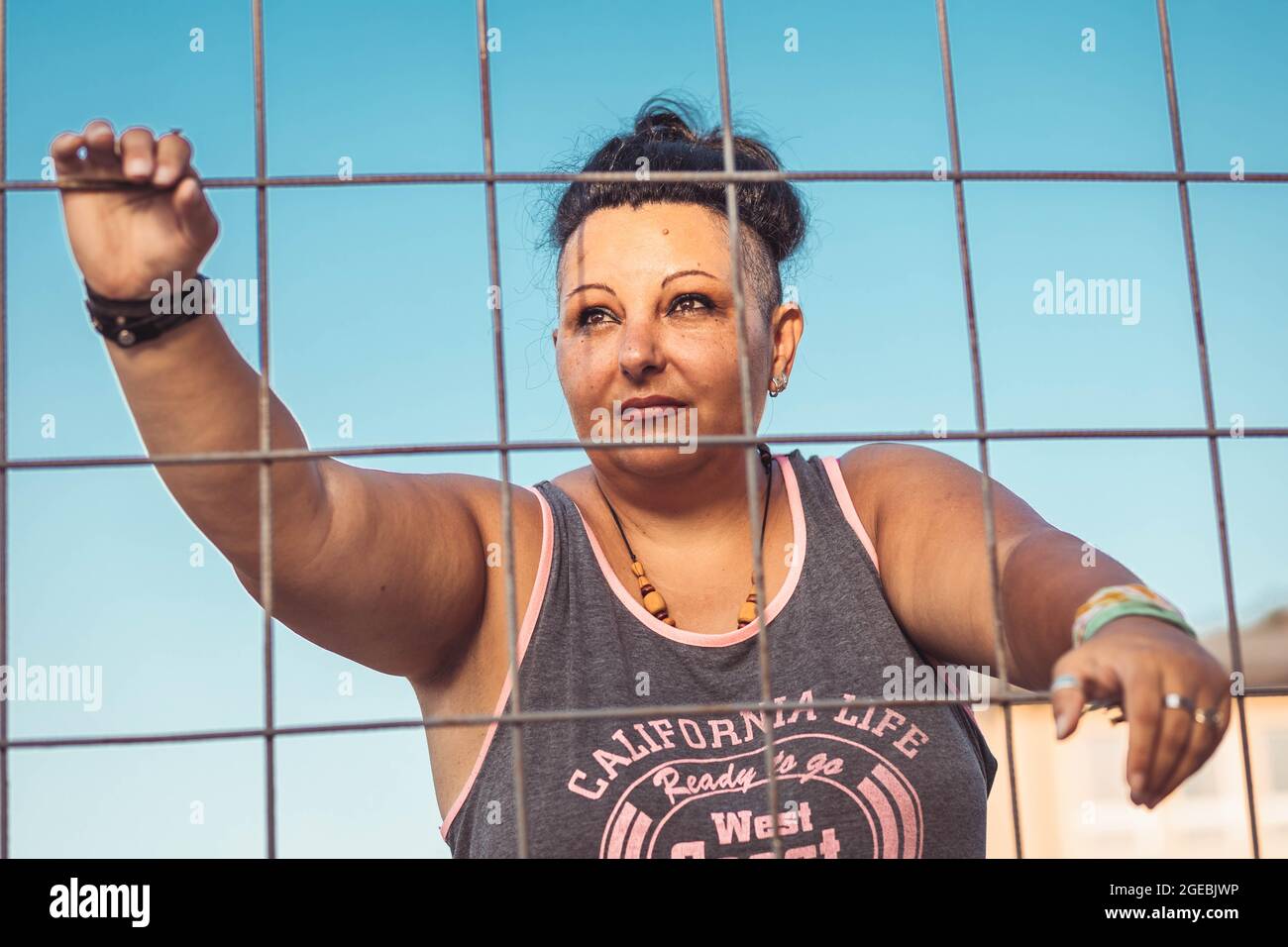 Donna di mezza età positiva con taglio cherokee. Guardare attraverso il filo Foto Stock