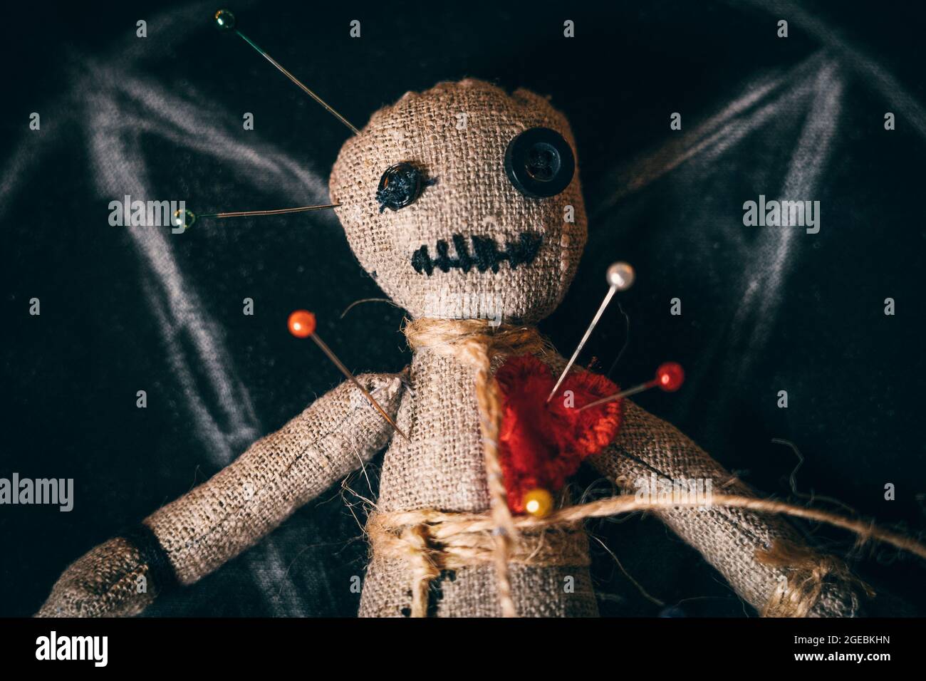 Voodoo strava la bambola con i bottoni invece degli occhi e con gli aghi, vista ravvicinata dall'alto. Foto Stock