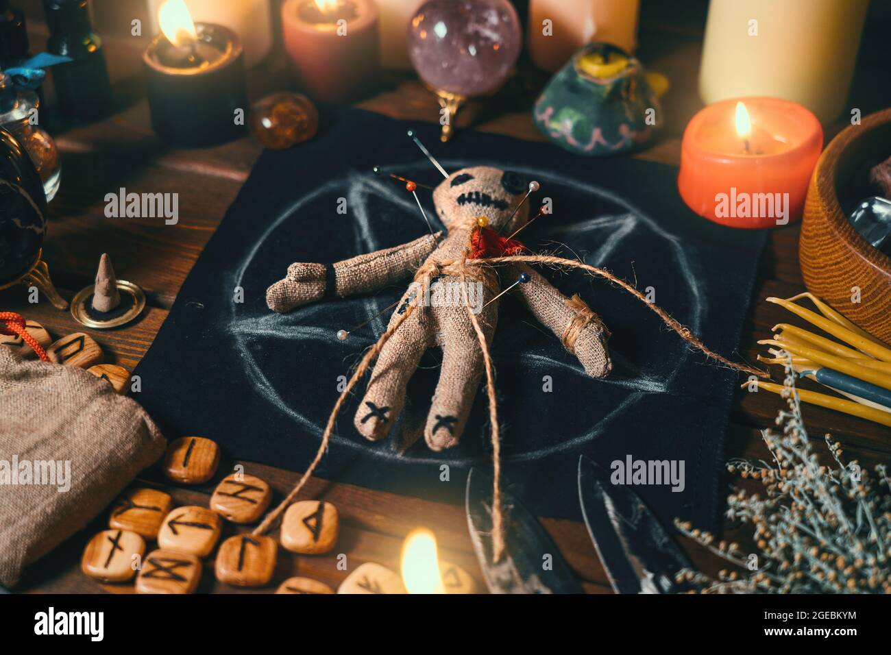 Voodoo bambola chiodata con aghi con cuore di straccio rosso traforato sul pentagramma e intorno a candele brucianti. Spooky o inquietante rituale esoterico magico. Foto Stock