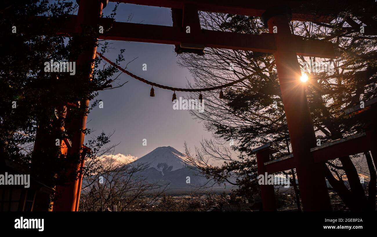 Tradizionali torii rossi e Fuji montagna con neve coperta al tramonto, bellissimo punto di riferimento luogo di viaggio. Stagioni invernali paesaggio giapponese con una porta Tori Foto Stock