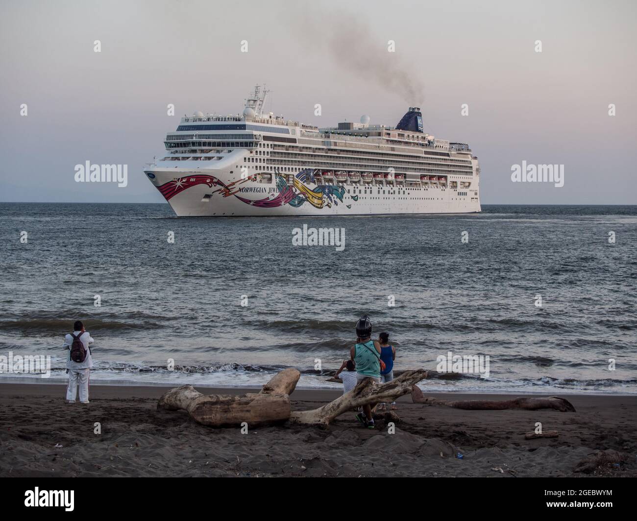 Gente locale sulla spiaggia guardando la nave da crociera Norwegian Jewel lasciando Puntarenas, Costa Rica. Foto Stock