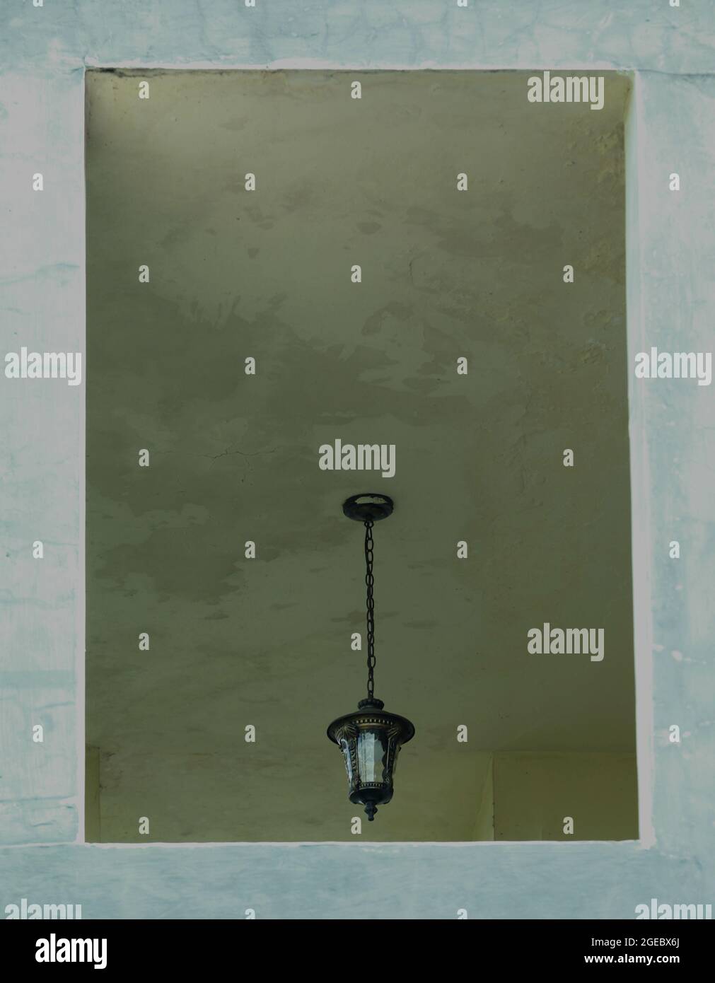 L'antica lampada che pende sul soffitto della casa con la parete frontale a forma di cornice Foto Stock