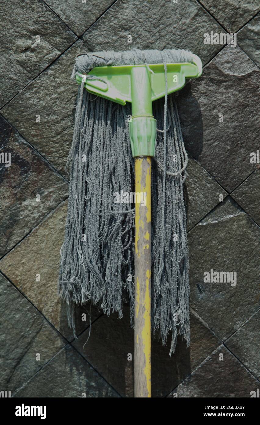 Primo piano di un mop manuale rotto su un muro di pietra Foto Stock