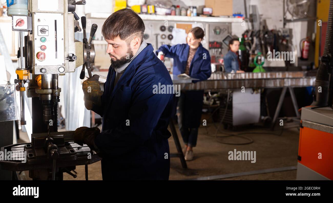 L'operatore di perforazione di parti metalliche su una macchina stazionaria Foto Stock