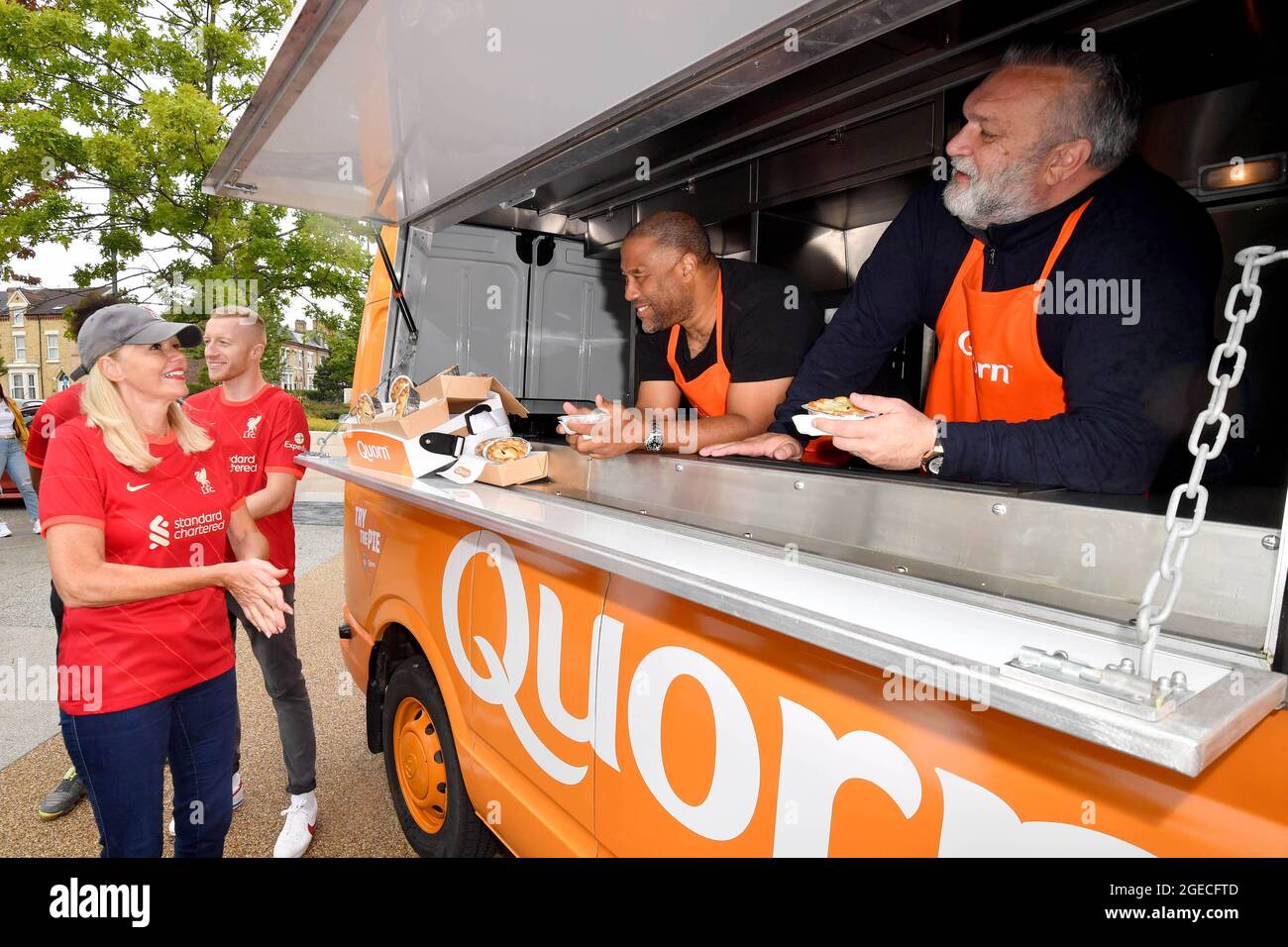 SOLO PER USO EDITORIALE (da sinistra a destra) i fan di Liverpool Carol May e Matthew Headon vengono serviti Quorn Meat-Free Steak Match Day Pies da ex calciatori, John Barnes e Neil Ruddock, allo stadio Anfield, prima della partita di sabato contro Burnley. Data di emissione: Giovedì 19 agosto 2021. Foto Stock