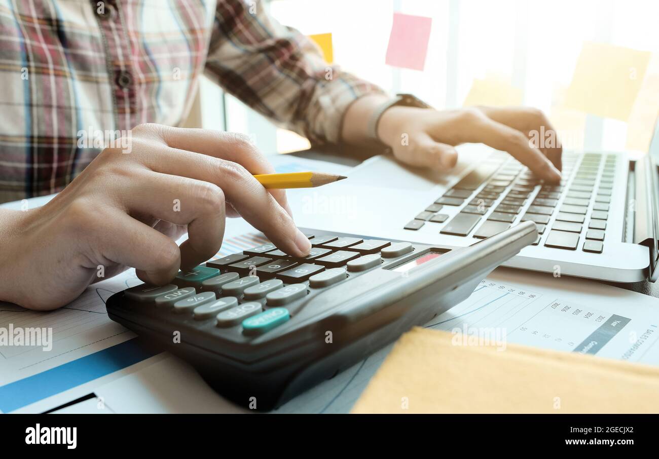 Donna d'affari che lavora in finanza e contabilità analizza il budget finanziario con calcolatrice e computer portatile in ufficio Foto Stock