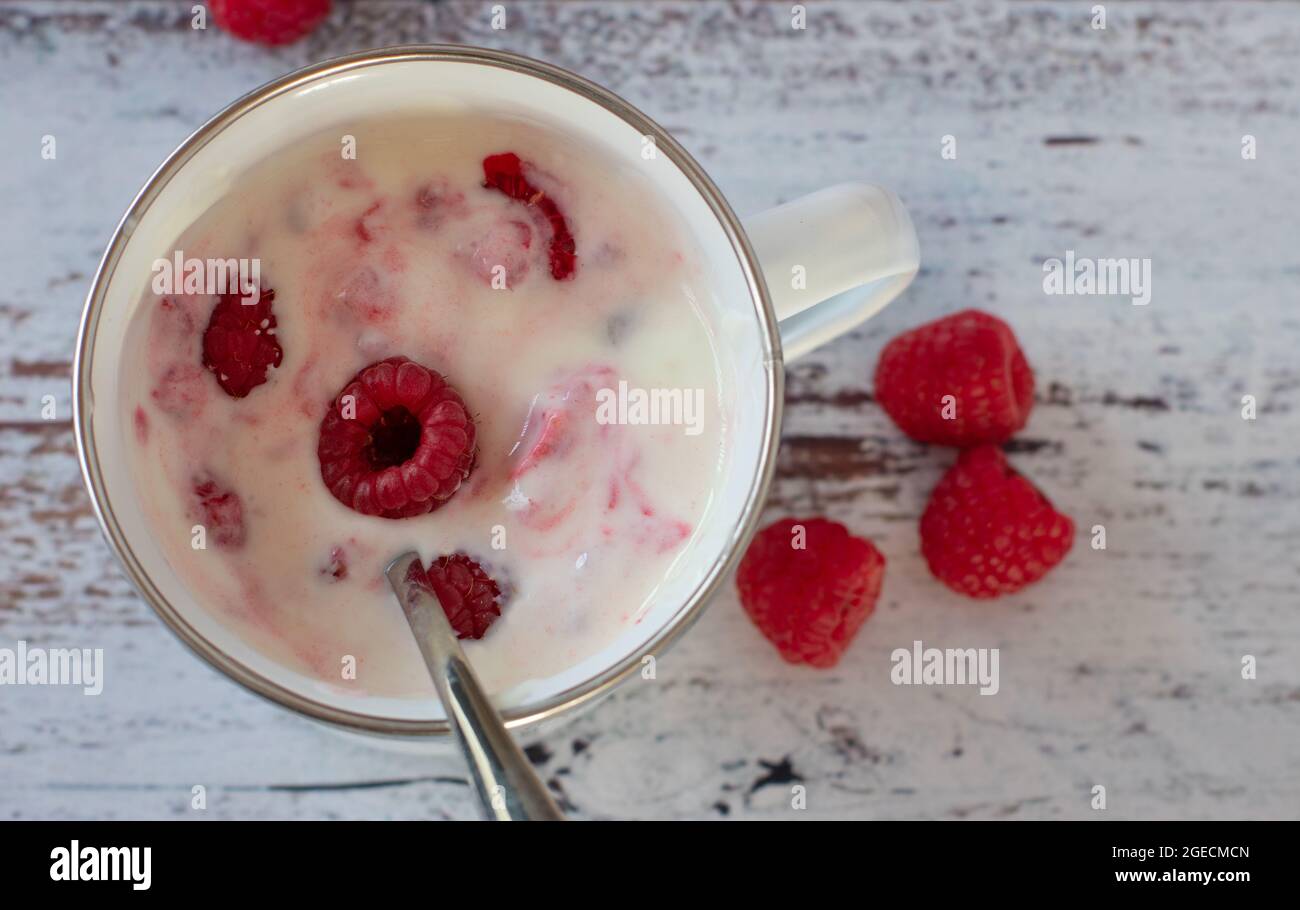 Yogurt al lampone in una tazza su sfondo chiaro con spazio per la copia Foto Stock