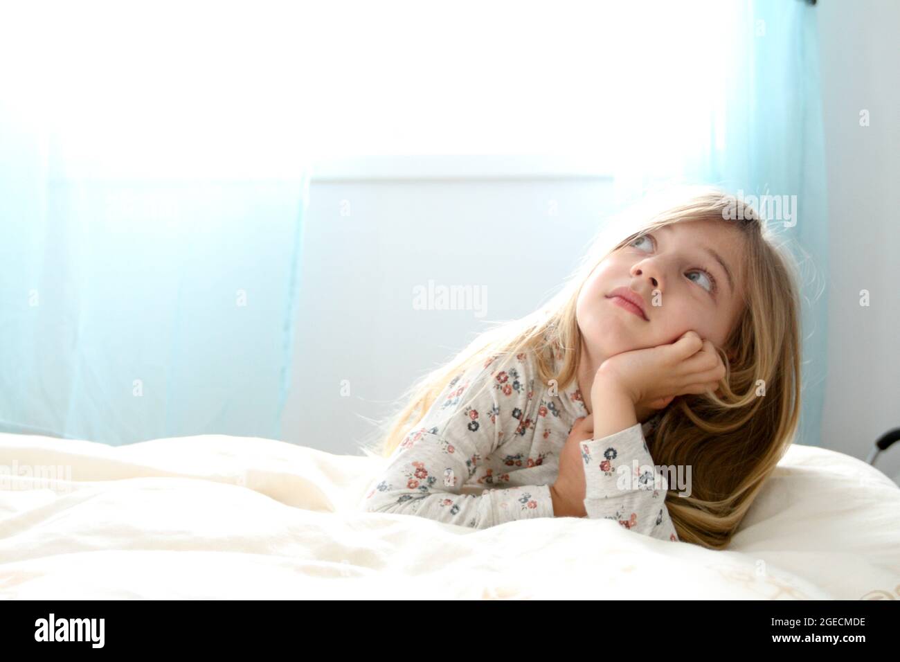 Giovane ragazza di sette sogni da giorno nella sua camera da letto Foto Stock