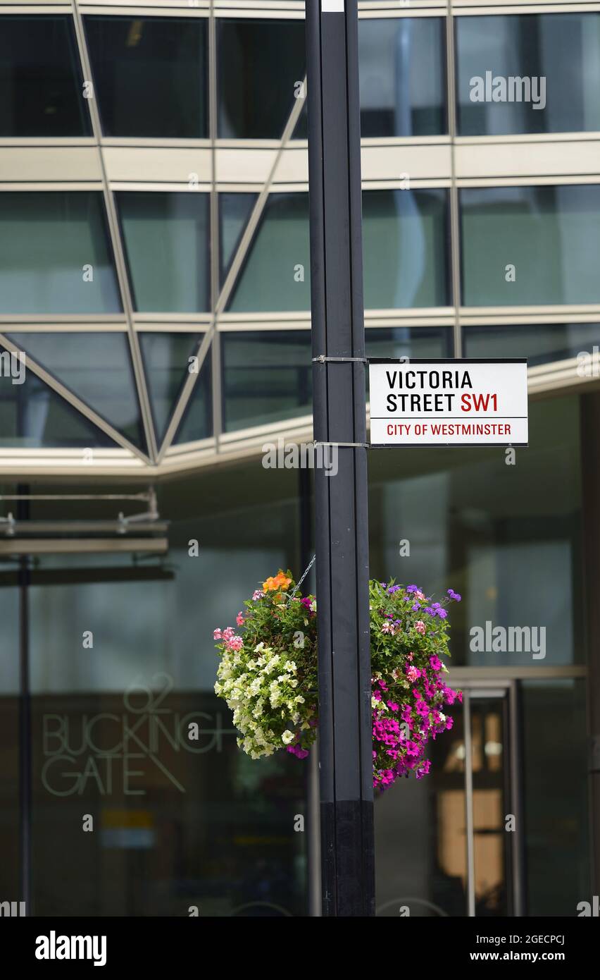 Londra, Inghilterra, Regno Unito. Cartello stradale: Victoria Street, City of Westminster, con fiori in cesti appesi Foto Stock