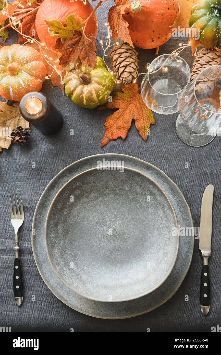 Halloween e Thanksgiving tavolo giorno impostazione con piatto grigio come mockup.festive cena decorazione foglie cadute, zucche su tovaglia di lino grigio. Superiore Foto Stock