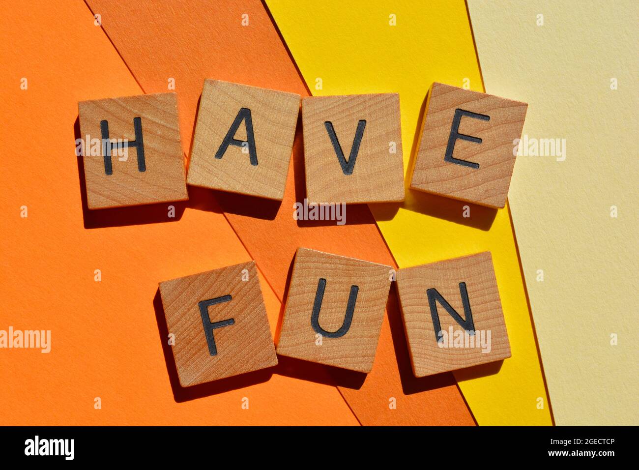 Buon divertimento, parole in lettere di legno isolate su sfondo giallo e arancione chiaro Foto Stock