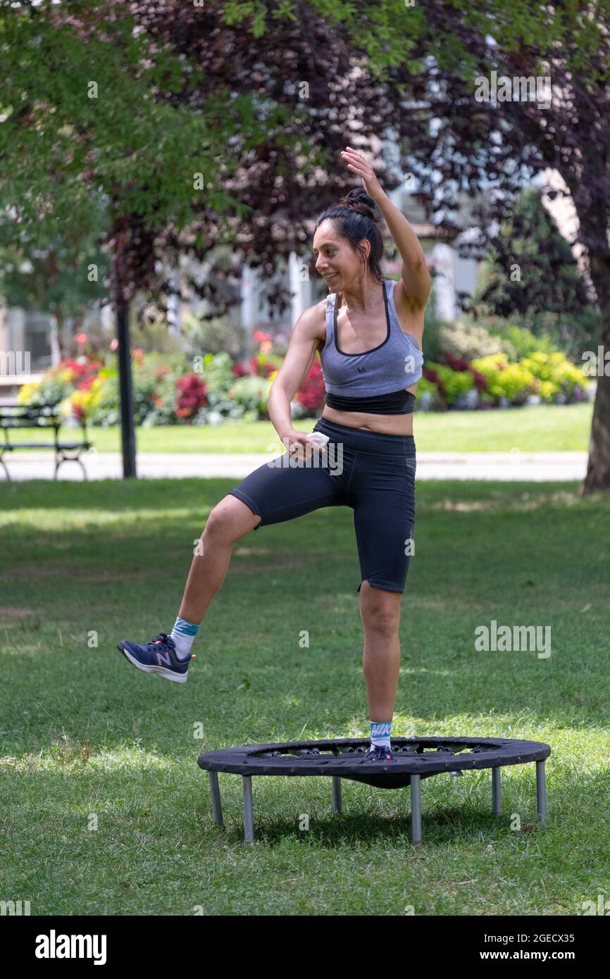 Una donna atletica molto in forma sorride durante una rigorosa classe Urban Rebounding in un parco a Queens, New York City Foto Stock
