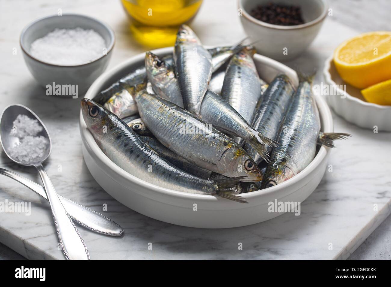 Sardine fresche, limone e sale in cucina, primo piano Foto Stock