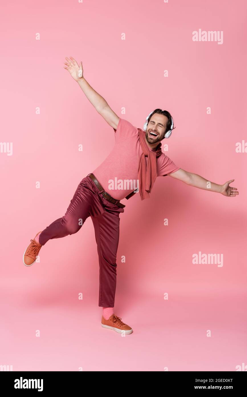 Uomo in cuffia che canta e balla su sfondo rosa Foto Stock