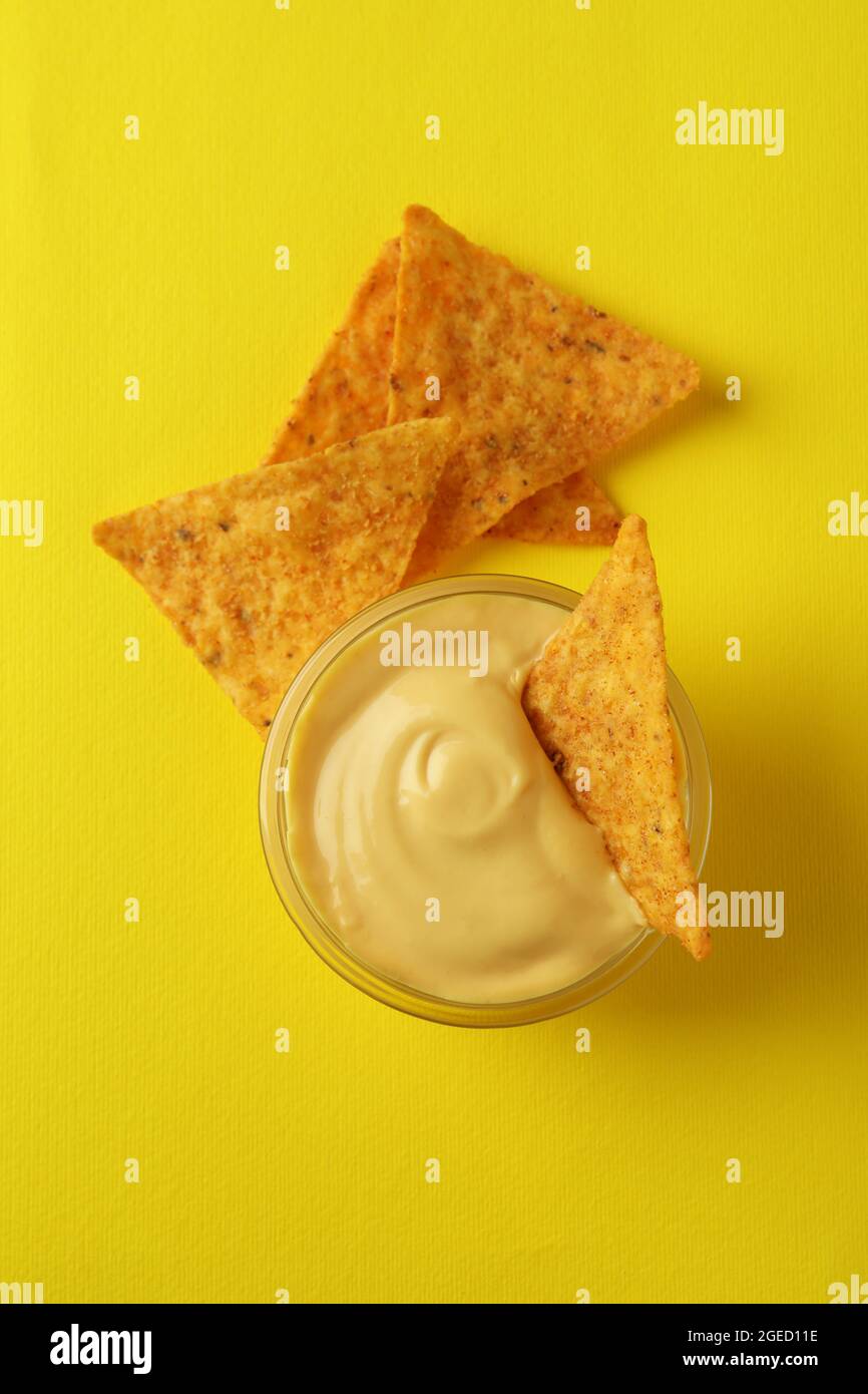 Ciotola con salsa al formaggio e patatine su sfondo giallo Foto Stock