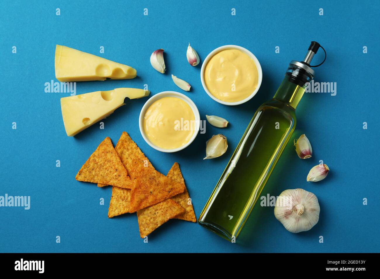 Salsa al formaggio, ingredienti e patatine su sfondo blu Foto Stock