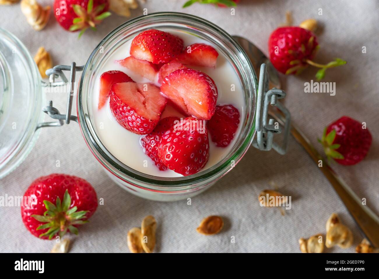 Fragole in vaso con latte su sfondo di legno chiaro. Vista dall'alto o dal piano portapaziente. Immagine sana del consumo Foto Stock