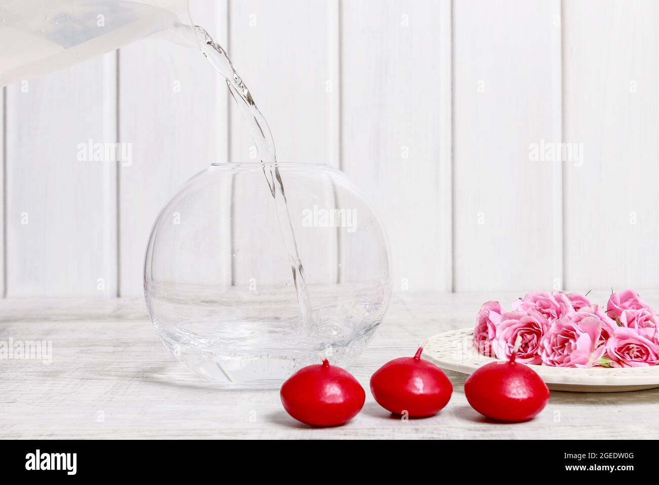 Fiorista al lavoro: Come fare la decorazione del giorno di San Valentino con rose rosa e candele galleggianti all'interno di una grande sfera di vetro. Passo per passo, tutorial. Foto Stock