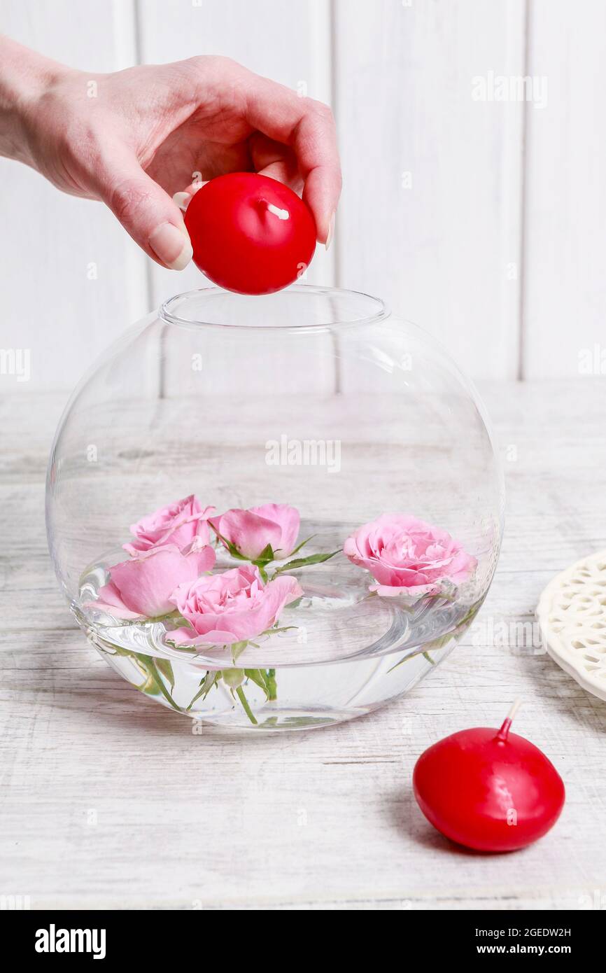 Fiorista al lavoro: Come fare la decorazione del giorno di San Valentino con rose rosa e candele galleggianti all'interno di una grande sfera di vetro. Passo per passo, tutorial. Foto Stock