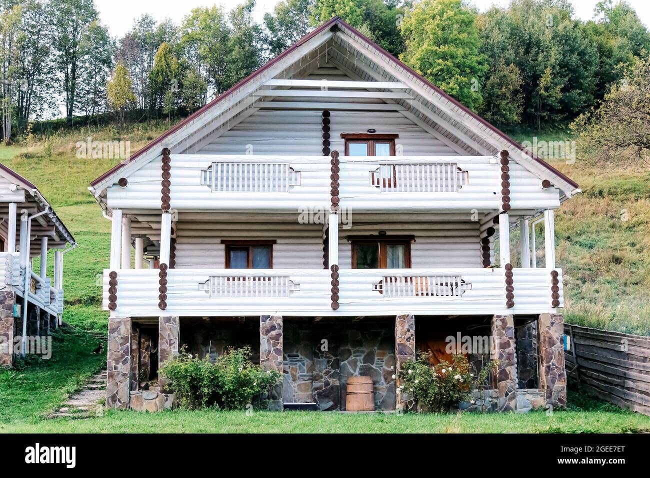 Chalet in legno bianco sulle colline di montagna. Bella casa in legno a due piani in estate sul lato della montagna. Esterno della casa in montagna Foto Stock