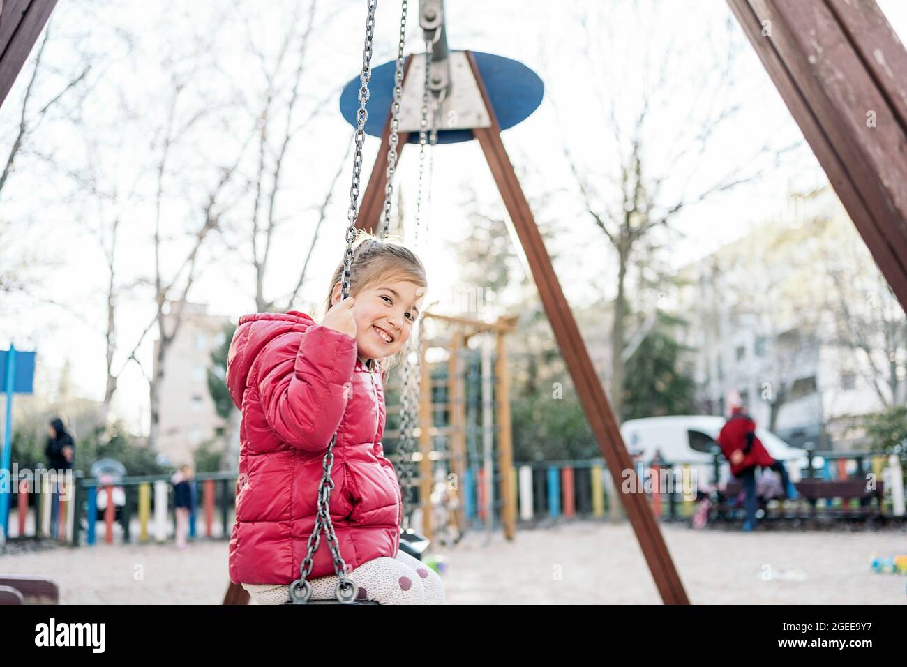 Una ragazza in età scolare sorridendo gioiosamente mentre si guida sul altalene nel parco Foto Stock