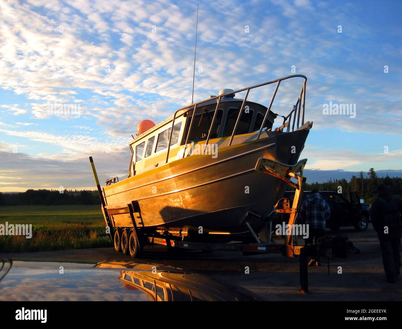 Il charter boat dell'Alaska si prepara al lancio all'alba. Il cielo è blu con le nuvole frastagliate. La barca si riflette nell'acqua. Foto Stock