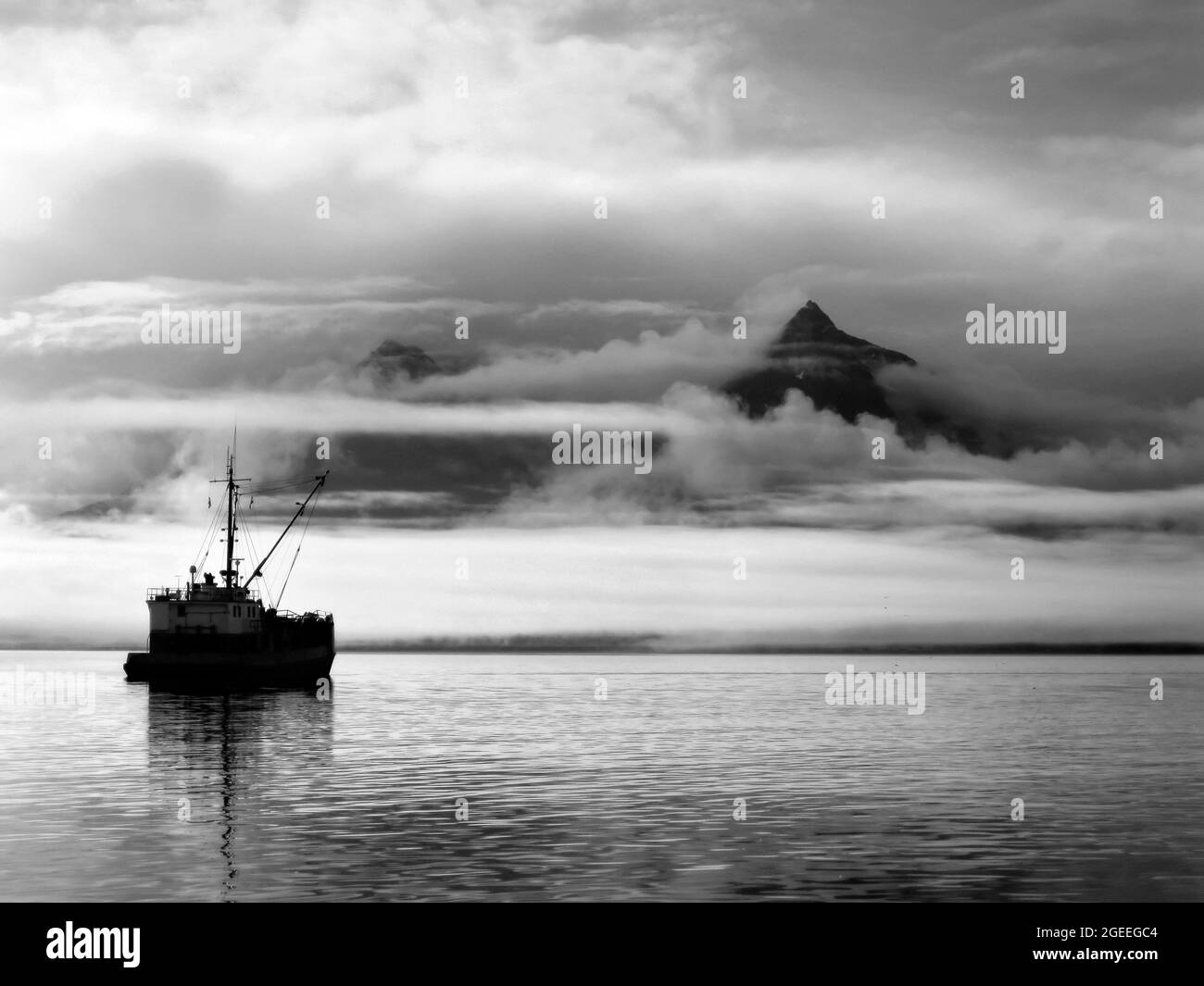 La nave si siede tranquillamente sull'acqua mentre l'alba colora le nuvole e la nebbia sopra la baia di Valdez in Alaska. Il cielo si azzera nell'angolo destro dell'immagine. Foto Stock