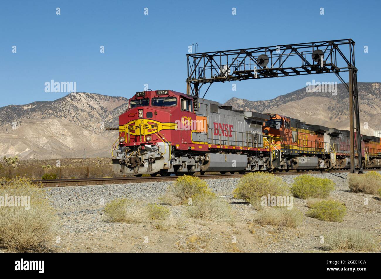 Il BNSF 4719 conduce un treno a Mojave, California, mentre passa sotto un ponte di segnale Foto Stock