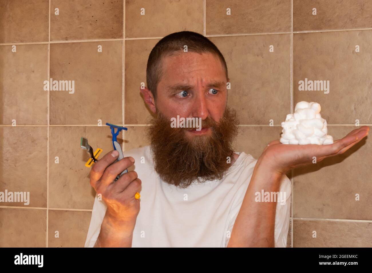 Vaduz, Liechtenstein 1 luglio 2021 un uomo con una barba grande sta in piedi in un bagno con il suo rasoio Foto Stock