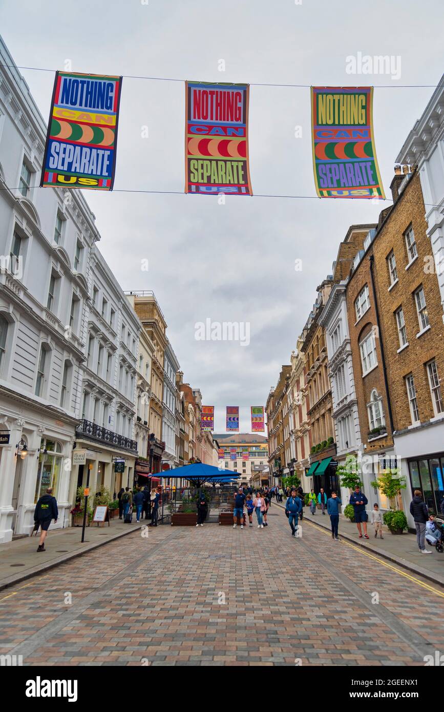 Londra, Regno Unito. 17 agosto 2021. Striscioni appesi a King Street, Covent Garden parte di un'installazione artistica "niente può separarci" dell'artista londinese Lakwena. Bandiere sulla trafficata King Street e Henrietta Street blasonate con messaggi positivi come Londra celebra l'inizio dell'estate e emerge dall'ultima fase di Lockdown e Floral Street con paletti colorati dipinti a mano. Credit: SOPA Images Limited/Alamy Live News Foto Stock