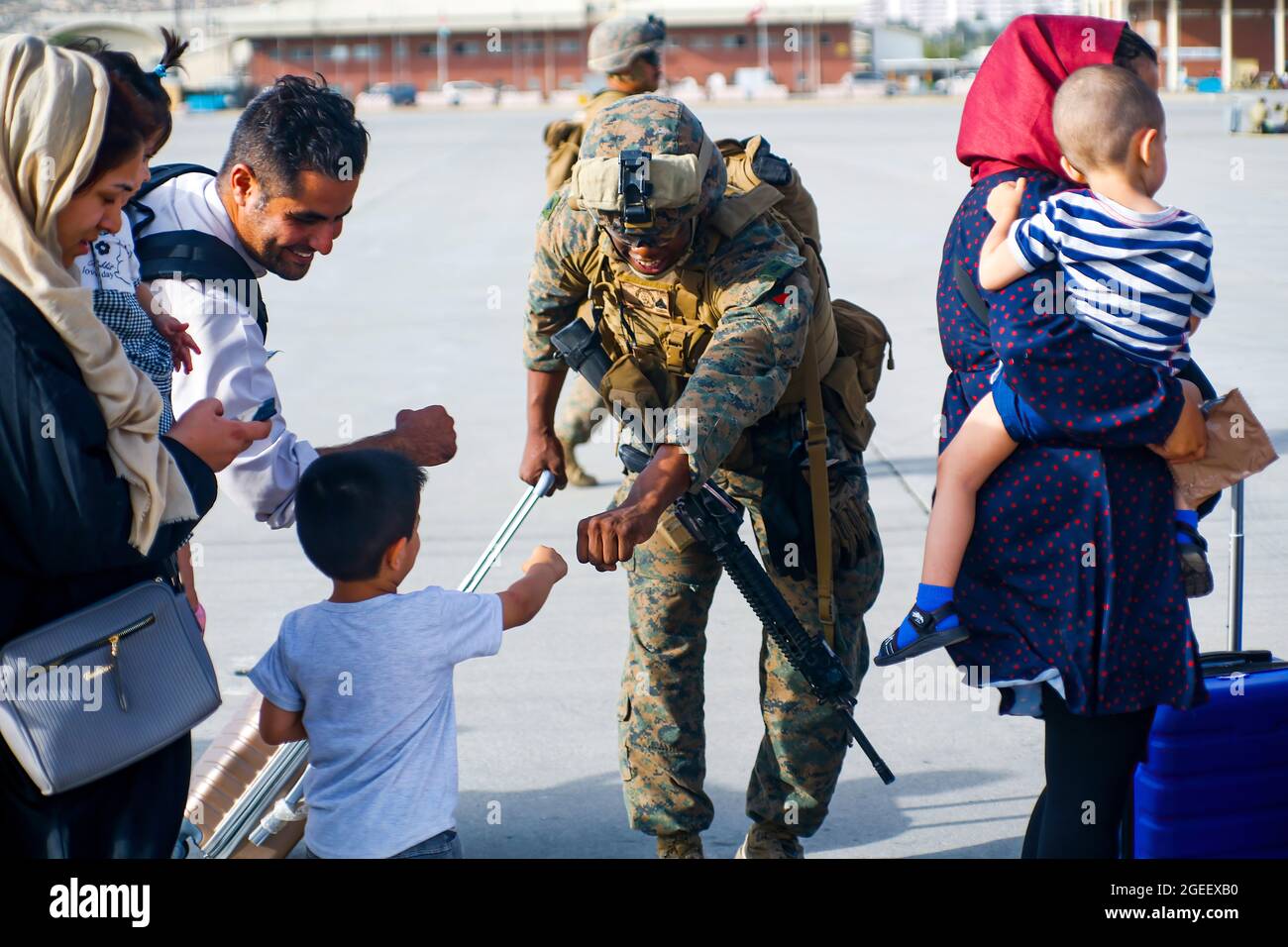 210818-M-JM820-1182 AEROPORTO INTERNAZIONALE DI HAMID KARZAI, Afghanistan (18 agosto 2021) – UNA marina statunitense assegnata alla 24a unità di spedizione marittima pugni un bambino evacuato durante un prelievo militare all'Aeroporto Internazionale di Hamid Karzai, Afghanistan, 18 agosto. I membri del servizio degli Stati Uniti stanno assistendo il Dipartimento di Stato con un ordinato prelievo di personale designato in Afghanistan. (STATI UNITI Marine Corps foto di Lance CPL. Nicholas Guevara) Foto Stock