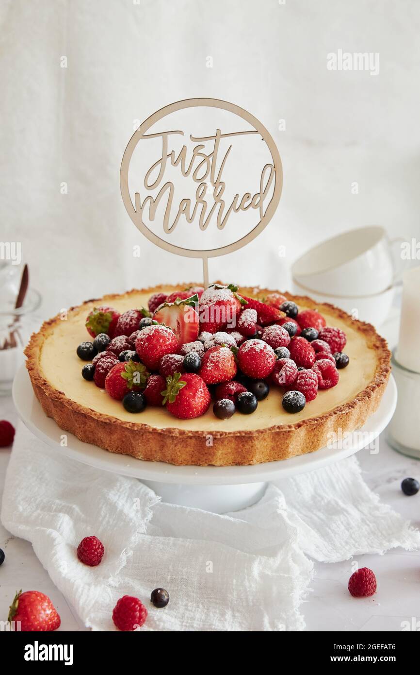 Deliziosa cheesecake con frutti di bosco freschi in cima e un topper che dice appena sposato Foto Stock