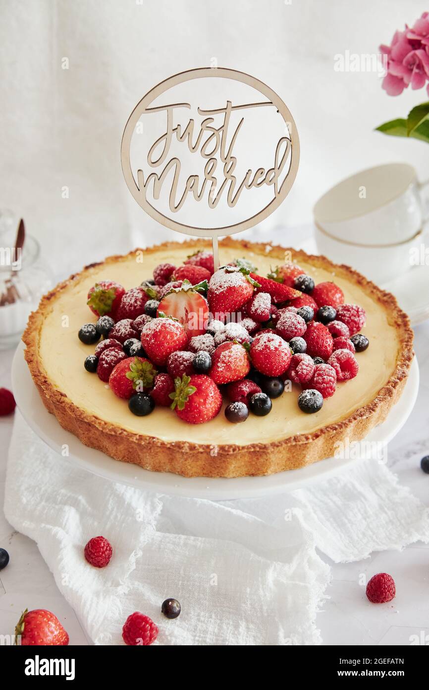 Deliziosa cheesecake con frutti di bosco freschi in cima e un topper che dice appena sposato Foto Stock