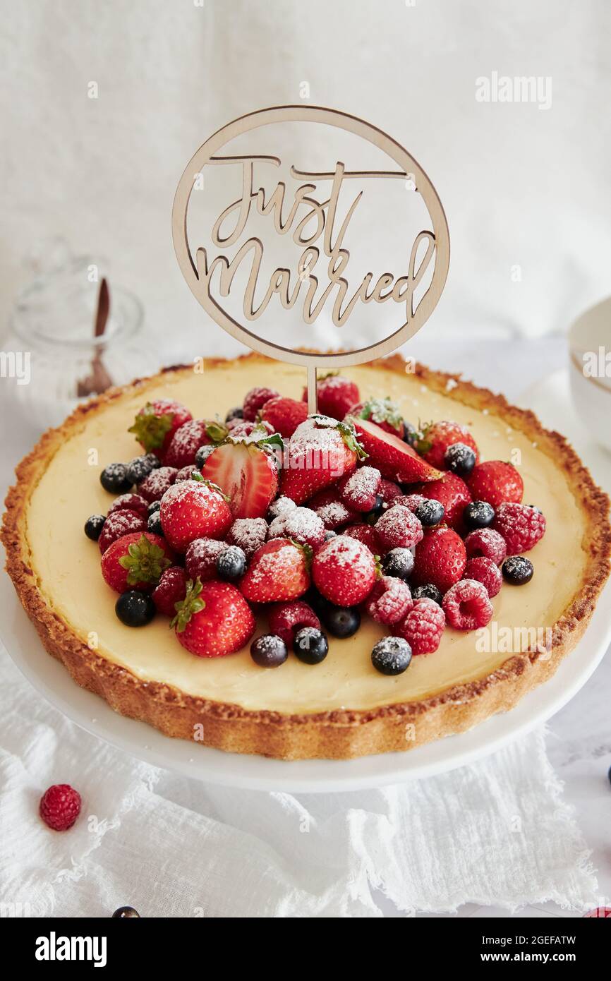 Deliziosa cheesecake con frutti di bosco freschi in cima e un topper che dice appena sposato Foto Stock