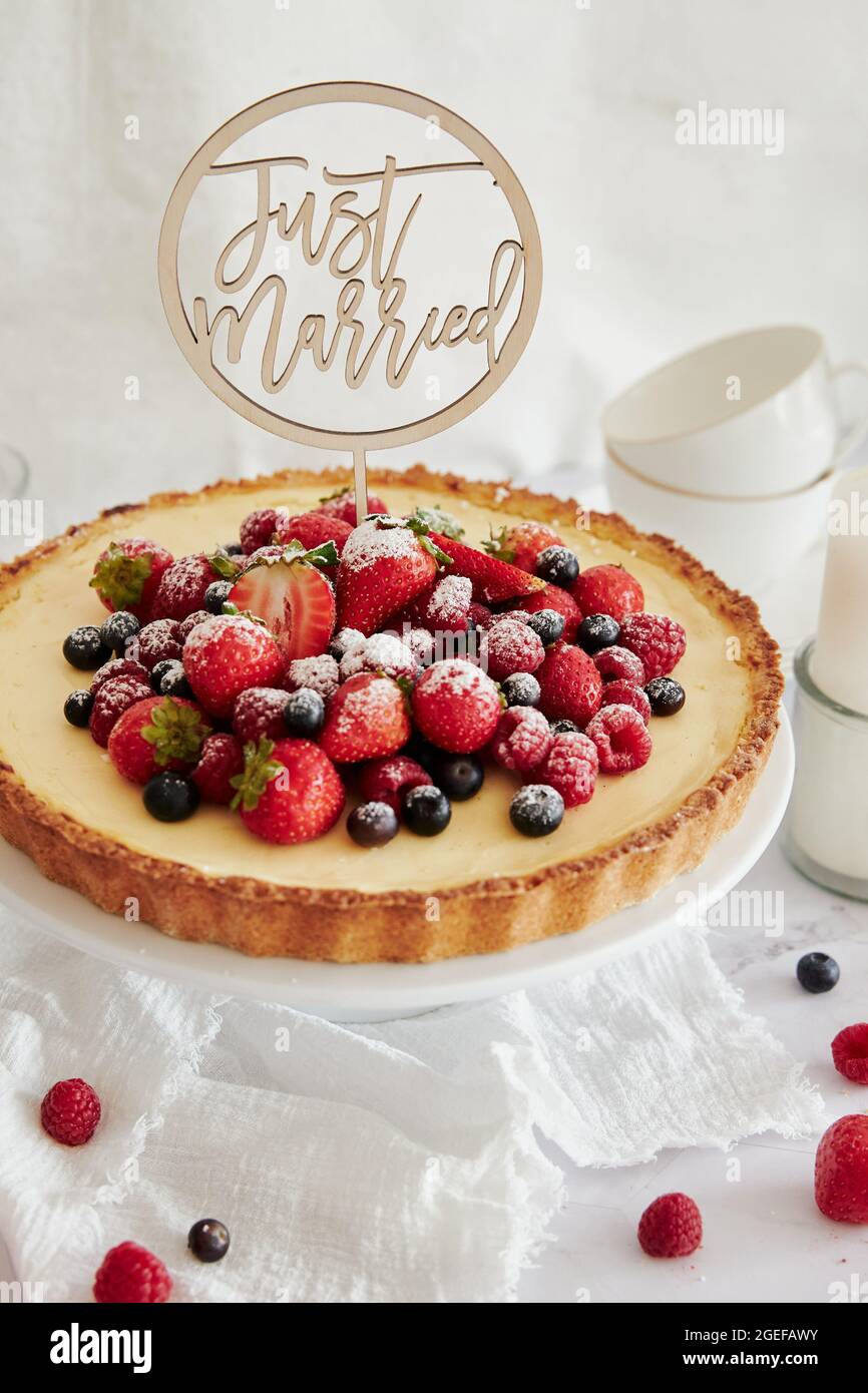 Deliziosa cheesecake con frutti di bosco freschi in cima e un topper che dice appena sposato Foto Stock