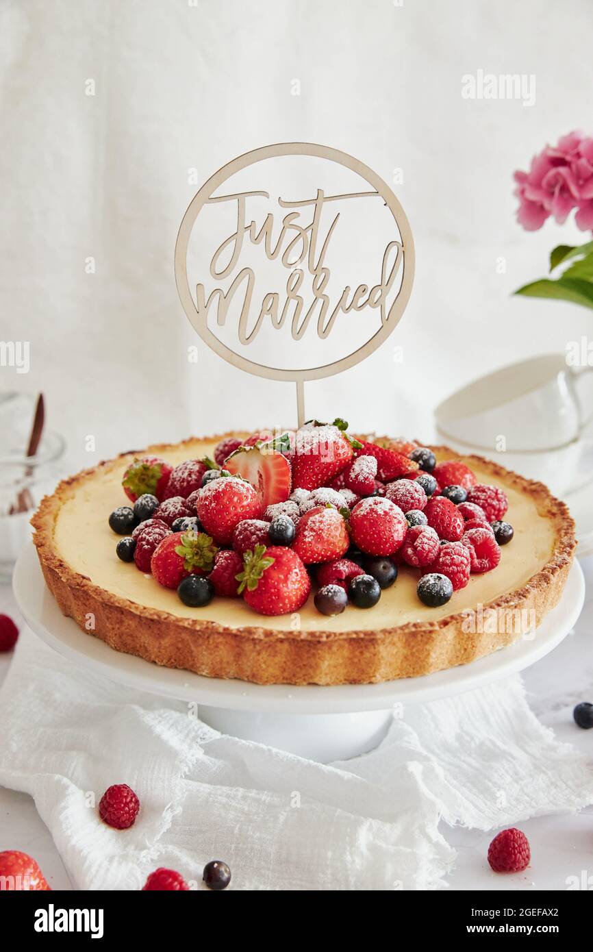 Deliziosa cheesecake con frutti di bosco freschi in cima e un topper che dice appena sposato Foto Stock