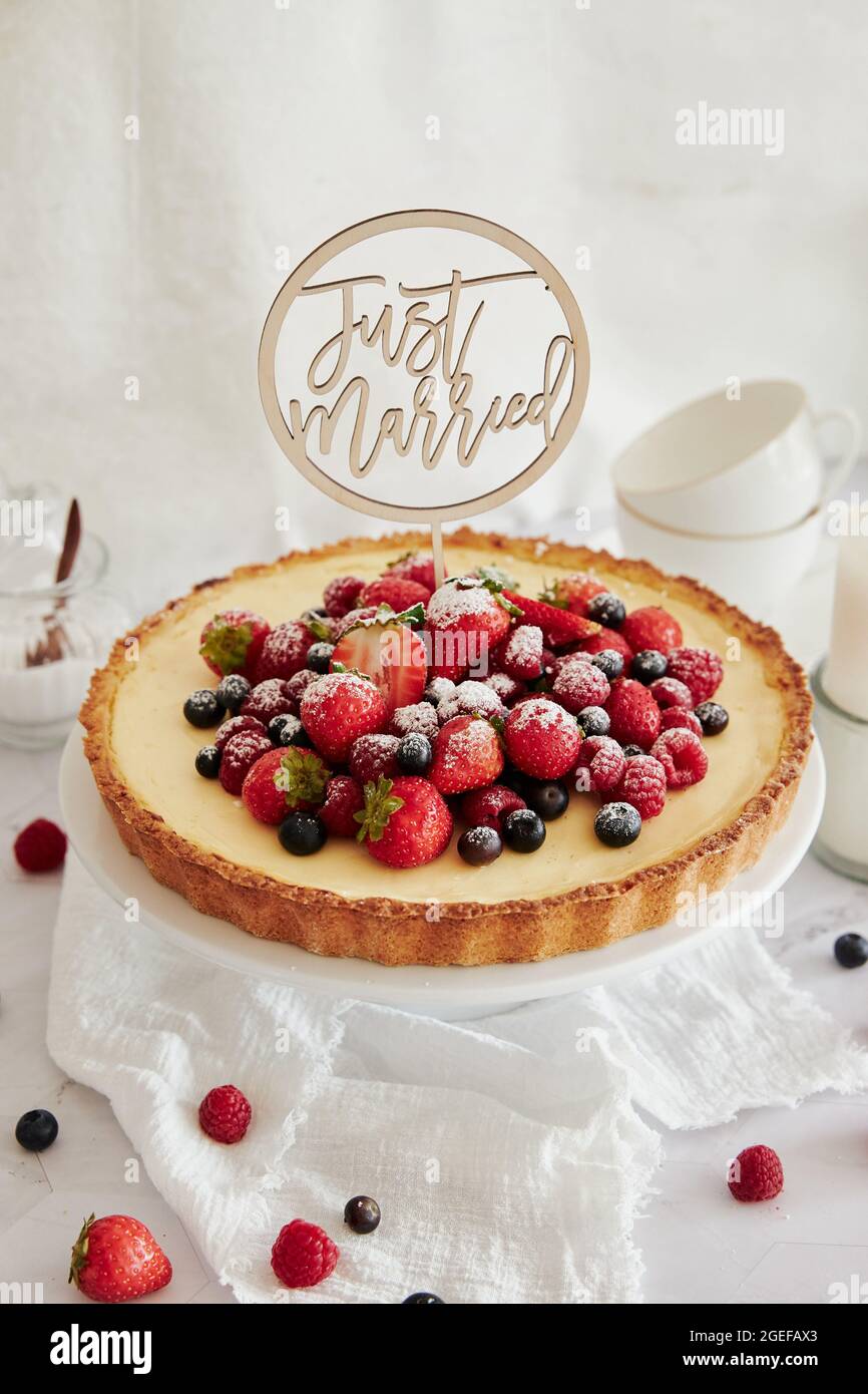 Deliziosa cheesecake con frutti di bosco freschi in cima e un topper che dice appena sposato Foto Stock