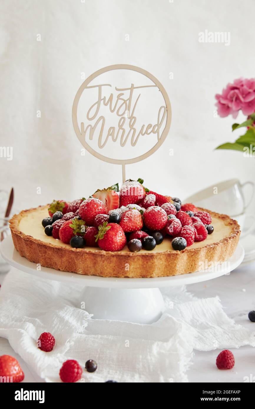 Deliziosa cheesecake con frutti di bosco freschi in cima e un topper che dice appena sposato Foto Stock